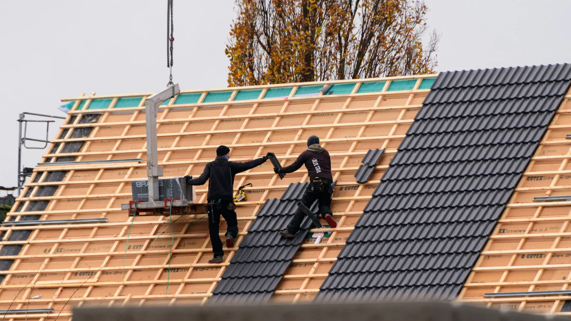 Couvreurs posant des tuiles sur une toiture neuve